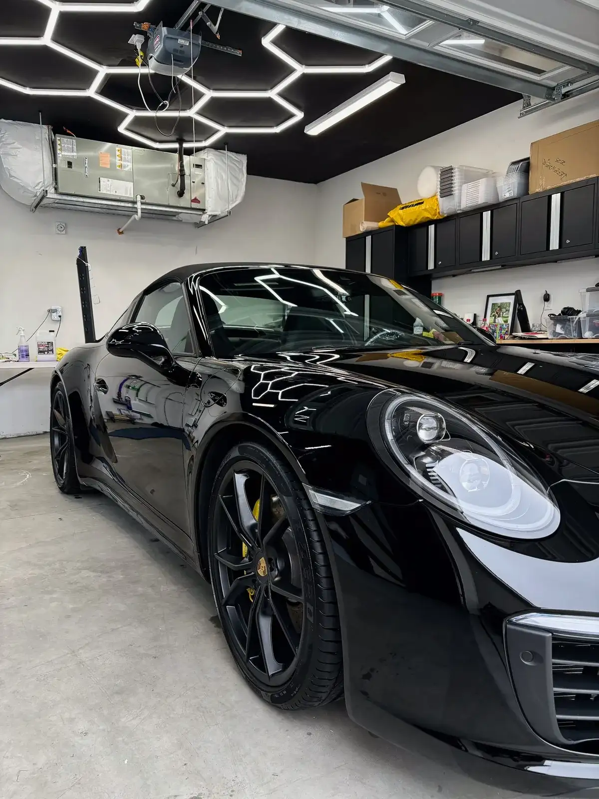 Hexagon garage lights reflected in the hood of a black Porsche 911 after a Premium Exterior Detail