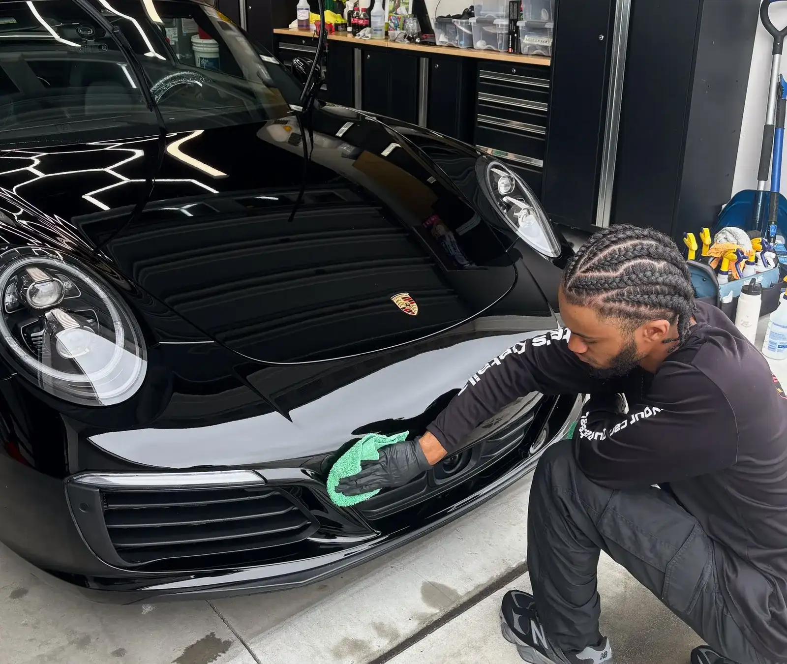 Nate hand-polishing the front of a black Porsche 911